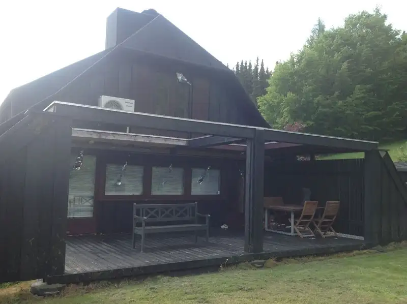 Sort træhus med overdækket terrasse og nyt tag