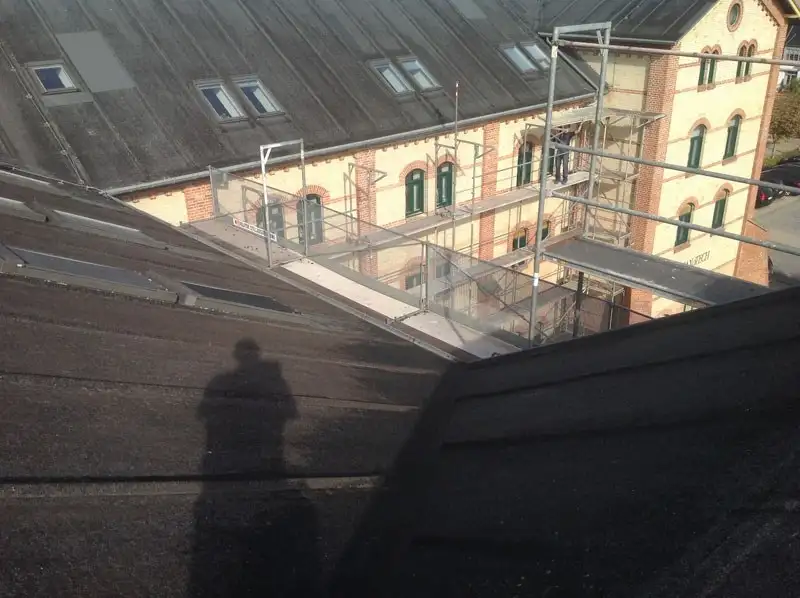 Stor bygning med stillads under tagarbejde, set fra taget